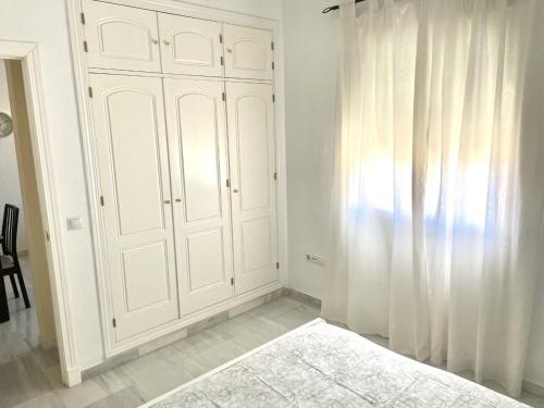 博尔穆霍斯Apartamento Liru Bormujos, a 5 minutos de Sevilla的一间设有白色橱柜和窗帘的房间