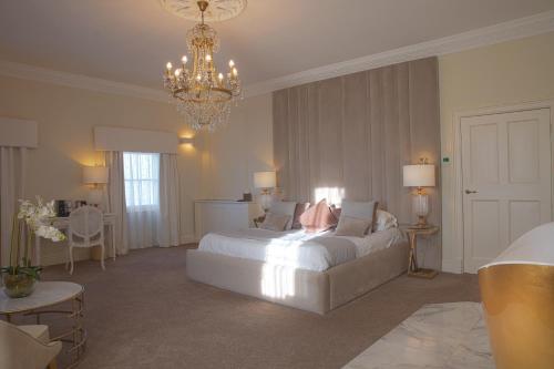 莱斯特Winstanley House的卧室配有一张白色大床和吊灯。