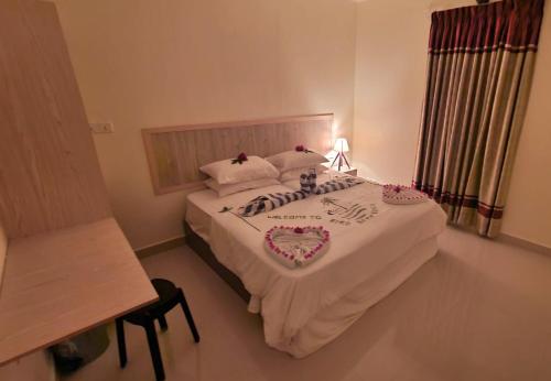 OmadhooBird Beak Beach的一间卧室配有一张铺有白色床单和鲜花的床。