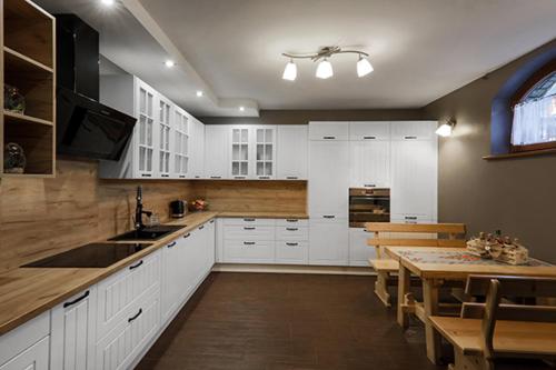 波罗宁Willa Dream B&B的厨房配有白色橱柜、桌子和用餐室。