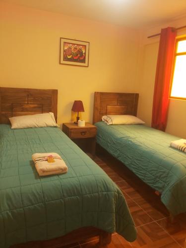 乌尤尼Beliz Inn的一间卧室设有两张绿色的床和窗户
