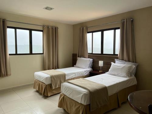 巴纳内拉斯Pousada Da Serra的带2扇窗户的酒店客房内的2张床