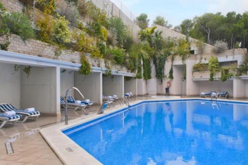 阿利坎特Apartamento Alicante Beach的一座带椅子的大型游泳池和一座建筑