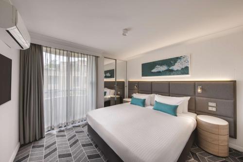 悉尼悉尼库吉海阿迪纳公寓式酒店的卧室配有带蓝色枕头的大型白色床