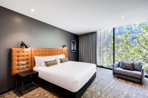 悉尼悉尼北部维伯酒店的一间卧室配有一张大床和一把椅子