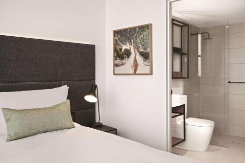 墨尔本Vibe Hotel Melbourne的一间带白色床的卧室和一间浴室