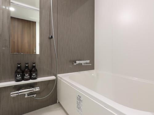 京都HOTEL M's EST KYOTO STATION SOUTH的浴室设有白色浴缸、水槽和镜子