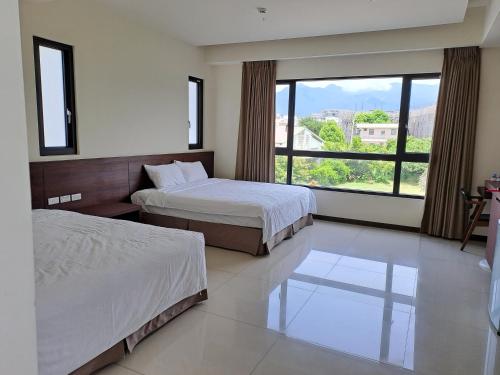 台东真善居民宿的酒店客房设有两张床和大窗户。