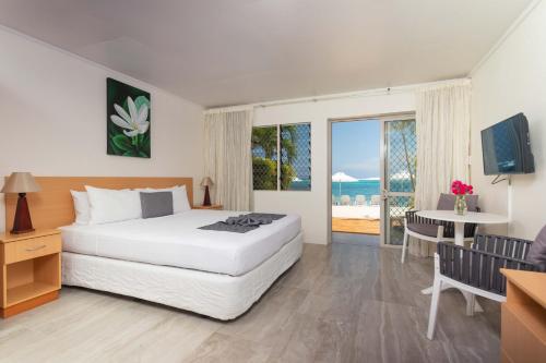 拉罗汤加莫阿纳金沙海滨公寓式酒店的一间卧室配有一张床、一张桌子和一个窗户。