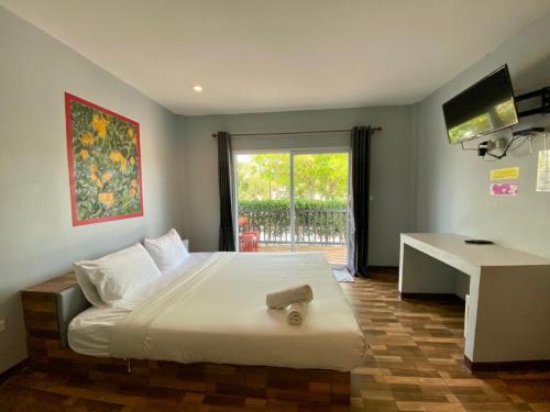 华富里Baan Ruay Suk Resort, Lopburi的一间卧室配有一张带书桌的床和窗户。