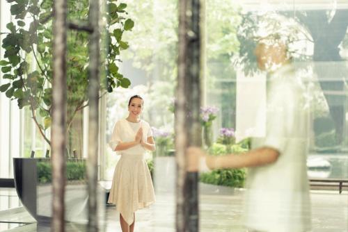 曼谷Four Seasons Hotel Bangkok at Chao Phraya River的站在窗前身穿白色衣服的女人