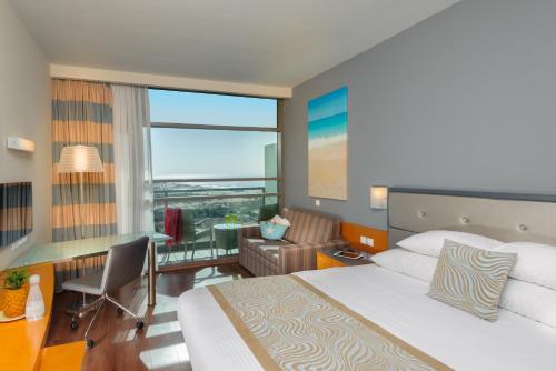 阿什杜德阿什杜德广场莱昂纳多酒店的配有一张床、一张书桌和一扇窗户的酒店客房