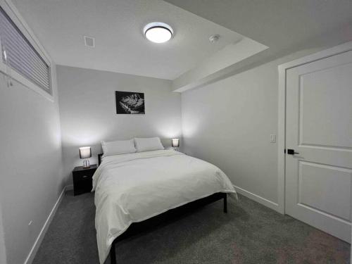 卡尔加里Cozy New Suite in NW Calgary的一间白色卧室,配有一张床和两盏灯