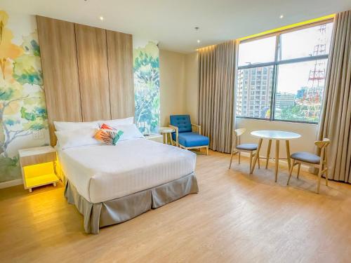 马尼拉Harolds Evotel Quezon City的酒店客房带一张床、一张桌子和椅子