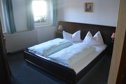 Burgstaedt诺曼斯餐厅及酒店的一间卧室配有两张带白色枕头的床