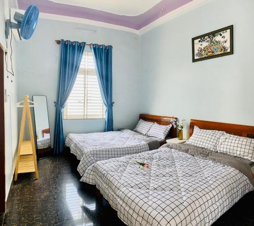 惹岛Homestay Tiên Tri 02的一间卧室设有两张床,窗户配有蓝色窗帘