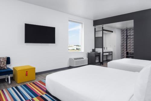 俄克拉何马城Aloft Oklahoma City Quail Springs的白色的客房配有床和电视。