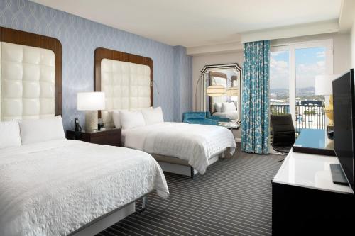 洛杉矶艾美德尔菲娜圣莫尼卡酒店的酒店客房设有两张床和一个阳台。