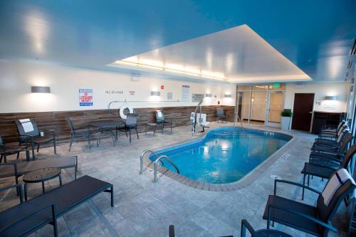 底特律莱克斯Fairfield Inn & Suites by Marriott Detroit Lakes的酒店客房的大型游泳池配有桌椅