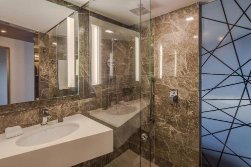 瓜达拉哈拉AC Hotel by Marriott Guadalajara Expo的一间带水槽和玻璃淋浴的浴室