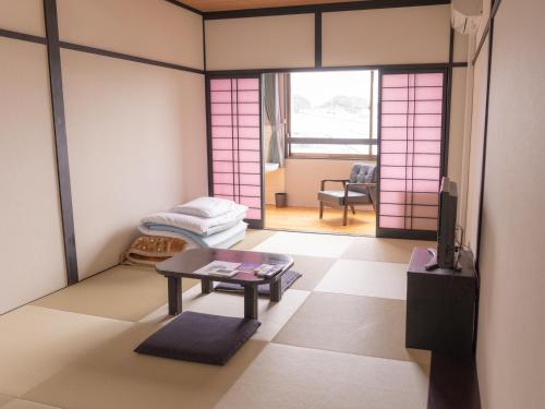 胜浦市若竹日式旅馆的一间设有桌子的房间和一间带粉红色门的房间