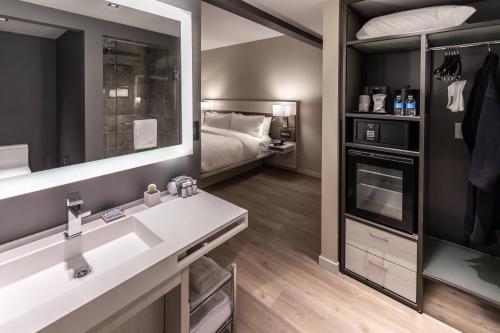 沃思堡AC Hotel by Marriott Fort Worth Downtown的浴室设有床、水槽和镜子