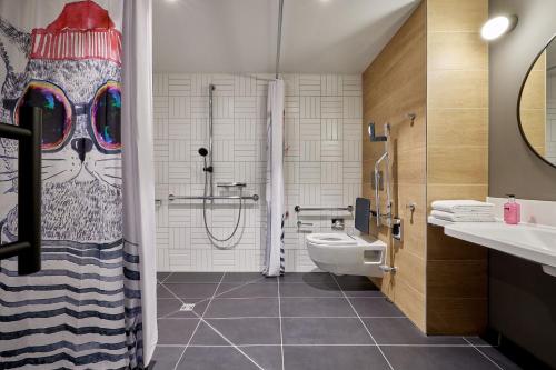 科隆Moxy Cologne Muelheim的浴室设有卫生间和带猫淋浴帘的淋浴。