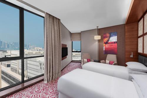 多哈Four Points by Sheraton Doha的酒店客房设有两张床和大窗户。