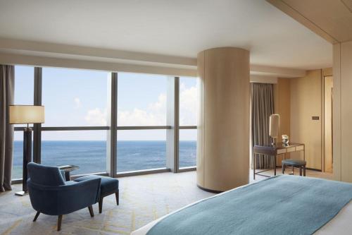 青岛青岛瑞吉酒店的一间卧室配有一张床、一把椅子和窗户。