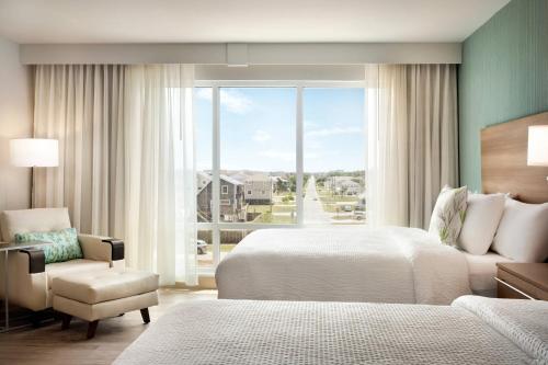 斩魔山TownePlace Suites by Marriott Outer Banks Kill Devil Hills的卧室配有床、椅子和窗户。