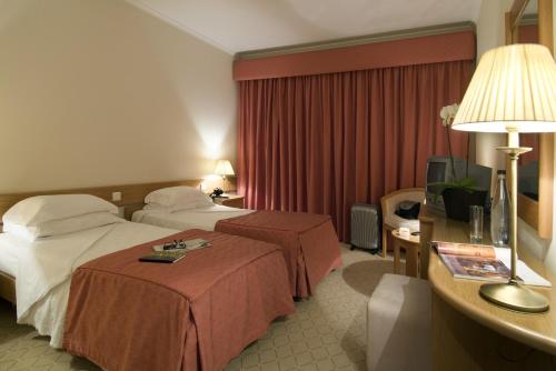 法蒂玛克鲁兹阿尔塔酒店的酒店客房设有两张床和一张带台灯的桌子。