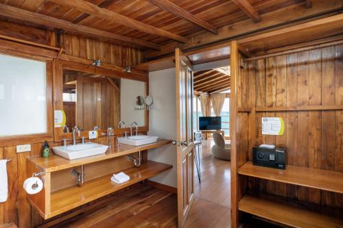阿约拉港Blu Galapagos Sustainable Waterfront Lodge的一间带两个水槽和木墙的浴室