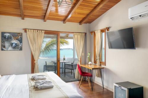 阿约拉港Blu Galapagos Sustainable Waterfront Lodge的一间卧室配有一张床、一台电视和一张桌子