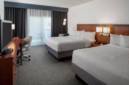 孟菲斯孟菲斯东/公园大道万怡酒店的酒店客房设有两张床、一张桌子和一台电视。