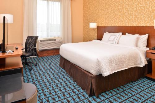沃伦斯堡Fairfield Inn & Suites by Marriott Warrensburg的酒店客房配有一张床、一张书桌和一台电视。
