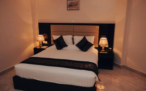 基加利Madras Hotel and Apartments的一间卧室配有一张带两盏灯的大型白色床。