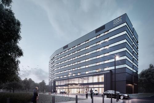 华沙Four Points by Sheraton Warsaw Mokotow的一座大型建筑,前面有停车位