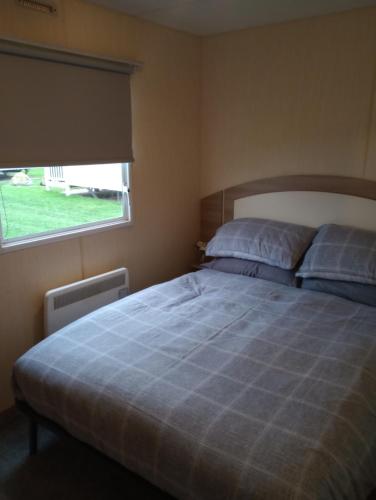 康威A22 is a 3 bedroom caravan on Whitehouse Leisure Park in Towyn near Abergele with decking and close to sandy beach的一间卧室设有一张大床和窗户