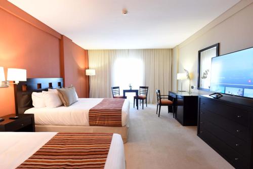 拉马约Camberland Resort & Spa Ramallo的酒店客房设有两张床和一台平面电视。