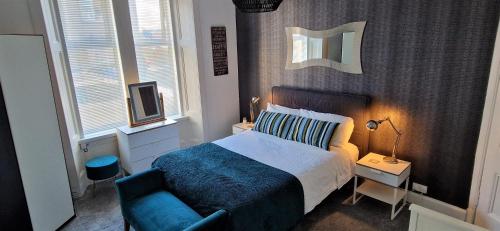 特伦Troon Beachcombers的一间卧室配有一张床和一张蓝色椅子
