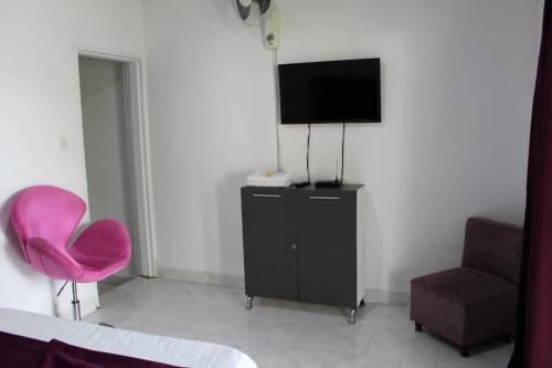 金巴亚Finca Hotel San Angello的配有电视和粉红色椅子的房间