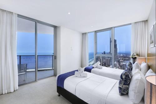 黄金海岸49th Floor Apartment with Ocean and Skyline Views sitting above the Hilton Hotel的带大窗户的客房内的两张床