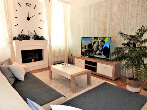 埃格尔Léna Apartman - Eger的带沙发、电视和时钟的客厅