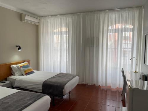 英雄港Hotel Ilha的酒店客房设有两张床和窗户。