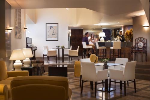 卡利亚里撒丁岛套房和餐厅酒店的大堂设有桌椅和酒吧。