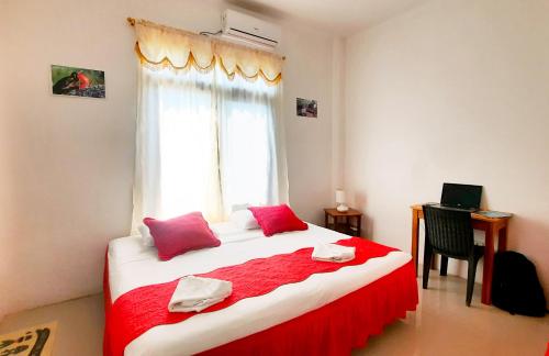 比亚米尔港Cielo Azul Galápagos Hotel的一间卧室配有一张带红色床单的大床和窗户。