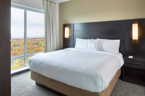 奥尔巴尼Residence Inn by Marriott Albany Airport的一张位于酒店客房的大床,设有大窗户