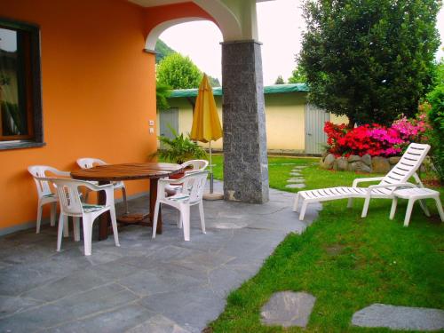坎诺比奥Appartamenti Girasole的庭院配有桌椅和遮阳伞。