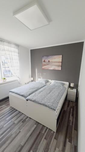 马里博尔Apartma4us的一间铺有木地板的白色卧室,配有一张床