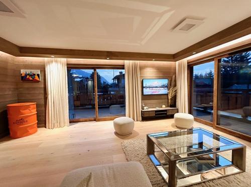 梅杰夫Les Chamois D’Arbois, Mont D’Arbois, Megève的客厅配有玻璃桌和电视